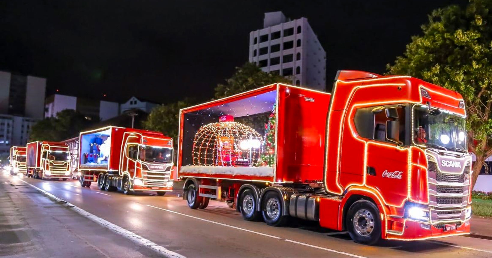 Caminh es iluminados da Caravana de Natal da Coca Cola passam em